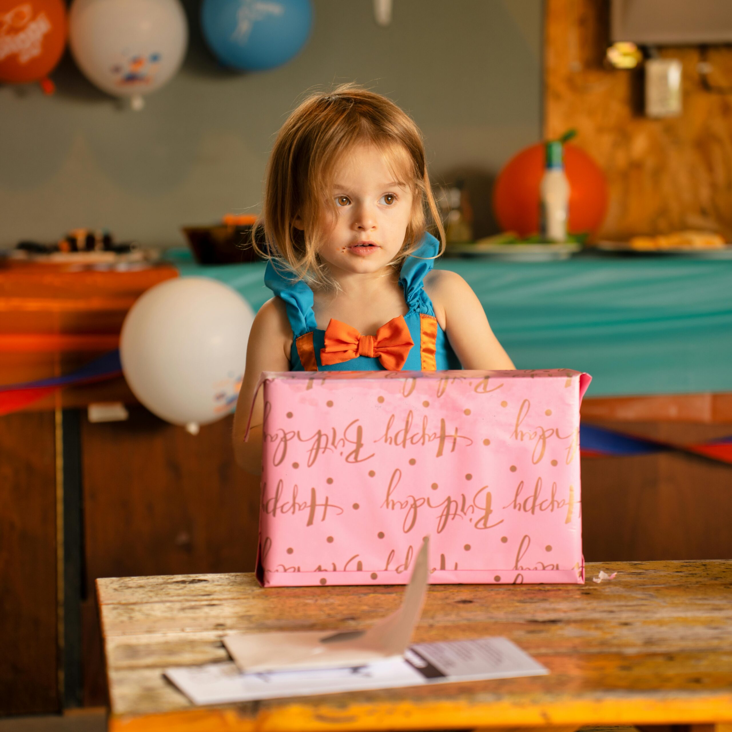 Adorable young girl with gift at a fun birthday celebration indoors.